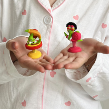 Dłonie prezentujące dwie kolorowe figurki Bob Snail z zestawu Eat&Play, kolekcjonerskie zabawki.