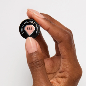 Semilac Second Skin Nude 583, okrągła nakrętka lakieru z beżowym rombem, w dłoni, białe tło.