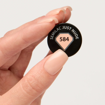 Kapturek lakieru hybrydowego Semilac Just Nude 584 w ciepłym beżu, trzymany w dłoni z pasującymi paznokciami.