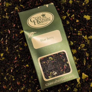 Zielona torebka herbaty Czas na Herbatę Blue Berry leży na czarnej herbacie liściastej z dodatkami.