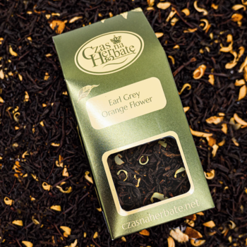 Zielona torebka herbaty Czas na Herbatę Earl Grey Orange Flower z widocznymi płatkami na tle liściastej herbaty.
