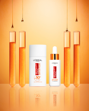 L'Oréal Revitalift Clinical SPF50+ UV fluid i serum z witaminą C, na tle probówek z pomarańczowym płynem.