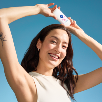 NIVEA Antyperspirant Fresh Flower 72h w białym sztyfcie, ujęcie uśmiechniętej kobiety z produktem nad głową.