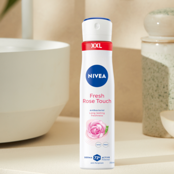 Antyperspirant NIVEA Fresh Rose Touch, biała butelka spray XXL z różą na tle łazienki, widok z przodu.
