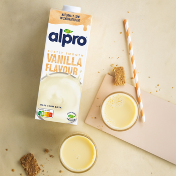 Alpro Smooth Vanilla Flavour roślinny napój sojowy w kartonie i szklankach na beżowym tle, niskotłuszczowy.
