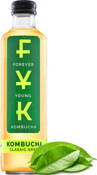 Butelka Forever Young Classic Green Kombucha z zieloną etykietą 'FYK', obok świeże liście zielonej herbaty, widok z przodu.