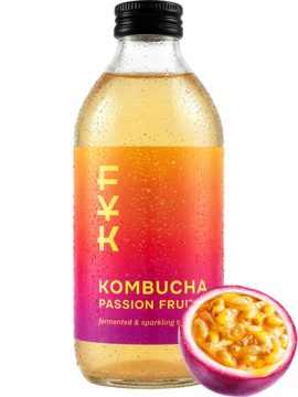 Kombucha Forever Young marakuja, złoty napój w szklanej butelce z gradientową etykietą, obok przekrojona marakuja.