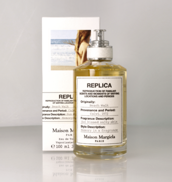Maison Margiela Replica Beach Walk woda toaletowa w szklanej butelce z żółtawą cieczą i białym pudełkiem, widok z przodu.
