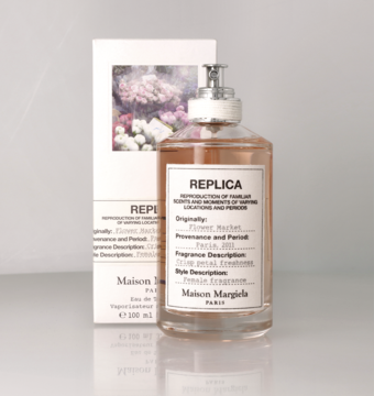 Maison Margiela Replica Flower Market woda toaletowa, szklana butelka z beżowym płynem, obok kwiatowe pudełko.