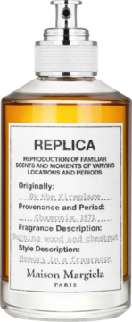 Woda toaletowa Maison Margiela Replica By the Fireplace, bursztynowy płyn w butelce z białą etykietą, widok z przodu.