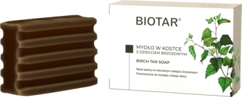 Ciemnobrązowe mydło dziegciowe Biotar w kostce, widoczne warstwy, obok białe opakowanie z liśćmi brzozy.