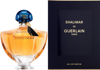 Orientalne perfumy Shalimar de Guerlain w bursztynowej butelce z niebieskim korkiem i czarną wstążką, obok ciemnego pudełka.