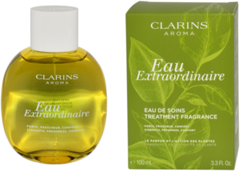 Pielęgnacyjny zapach Clarins Eau Extraordinaire. Obła butelka z żółtym płynem i zielone pudełko z liśćmi. Widok z przodu.