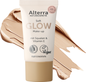Beżowa tuba podkładu Alterra Soft Glow Make-up 01 Ivory, z białym korkiem, na tle rozmazanych próbek produktu.