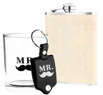 Zestaw "MR.": szklanka, czarny brelok z wąsem i piersiówka z drewnianym wykończeniem, na białym tle.