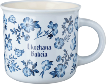 Biały ceramiczny kubek z uchwytem, zdobiony niebieskimi kwiatami i napisem "Ukochana Babcia", widok z przodu.