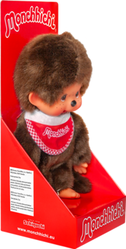 Pluszak Monchhichi, brązowa małpka z czerwonym śliniakiem w kratkę, w czerwonym tekturowym pudełku, widok z przodu.