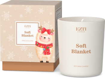 EZTI Soft Blanket soy candle w kremowym słoju, złote logo, obok beżowego pudełka ze świątecznymi płatkami śniegu i owieczką.