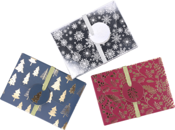 Trzy świąteczne pudełka prezentowe: czarne ze śnieżynkami, granatowe w choinki, bordowe w liście, ułożone w stos.