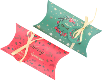 Dwa świąteczne pudełka prezentowe typu poduszka: zielone z wieńcem i czerwone z listkami, ze złotym napisem.