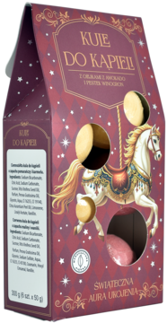 Świąteczne kule do kąpieli z olejem awokado w bordowym pudełku. Złoty karuzelowy koń, widoczne złote i różowe kule.