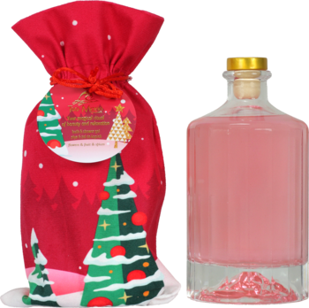 Czerwona torba prezentowa z choinkami obok butelki różowego ginu ze złotą nakrętką i korkiem, gotowa do wręczenia.