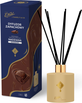 Dyfuzor E. Wedel Nadziana deserowa, złota butelka z patyczkami obok ciemnoniebieskiego pudełka z czekoladą.