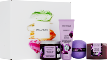 Organique Black Orchid zestaw spa: fioletowy balsam shea, krem, mydło, kula do kąpieli na tle barwnych smug.