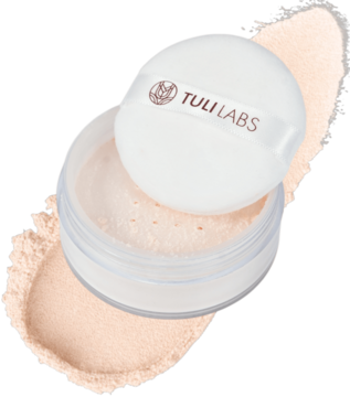 Puder sypki Tuli Labs Light Beige, otwarte opakowanie z puszkiem na tle rozsypanego pudru. Matowe wykończenie.