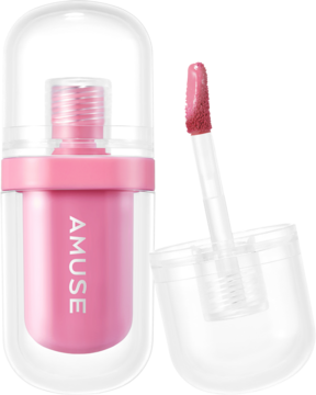 Różowy błyszczyk do ust Amuse w kapsułkowym etui, obok otwarty aplikator z błyszczykiem.