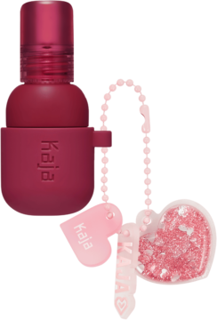 Kaja Jelly Charm Cherry Spritz: ciemnoczerwona pomadka/róż 2w1 z różowym breloczkiem z sercami. Widok z przodu.