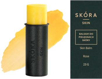 Skóra Skin: żółty balsam do pielęgnacji skóry w czarnym sztyfcie, obok ciemnozielone pudełko produktu, 23g.