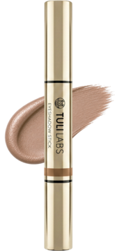 Złoty TULI LABS Eyeshadow Stick z błyszczącym, kremowym cieniem szampańskim i swatch'em na czarnym tle.