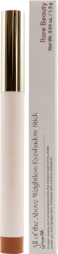 Rare Beauty Weightless Eyeshadow Stick w kolorze Growth, beżowy sztyft ze złotą nakrętką, obok pudełko.