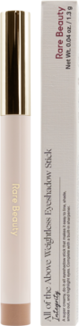 Kremowy beżowy cień w sztyfcie Rare Beauty Weightless Eyeshadow Stick Integrity obok pudełka.