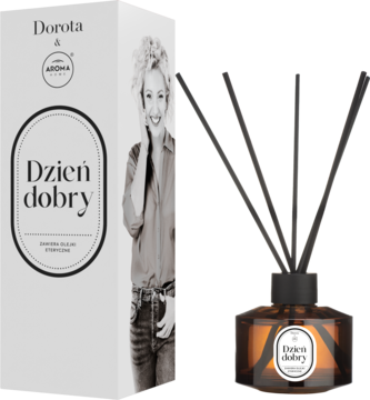 Dyfuzor zapachowy Dorota & AROMA "Dzień dobry" w bursztynowej butelce z patyczkami; obok białe pudełko z kobietą.