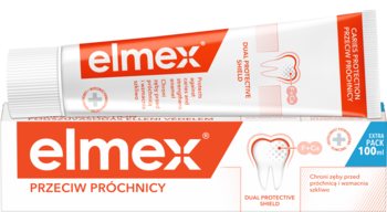 Biała tubka pasty Elmex Przeciw Próchnicy 100ml z pomarańczowym logo, leży przed białym kartonikiem, widok z przodu.