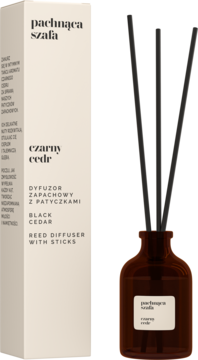 Dyfuzor zapachowy "Pachnąca Szafa Czarny cedr" z czarnymi patyczkami w bursztynowej butelce i beżowym pudełku.