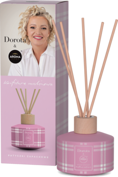 Różowy dyfuzor zapachowy Aroma Home Dorota Szelągowska, z patyczkami, obok pudełka w kratkę, zapach malinowy.