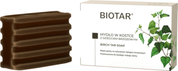 Ciemnobrązowe mydło dziegciowe Biotar w kostce, widoczne warstwy, obok białe opakowanie z liśćmi brzozy.