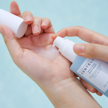 Dłoń dozująca nawilżające serum Skin1004 Centella Hyalu-Cica z pompką, widoczne białe serum na skórze.
