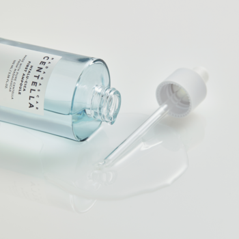 Skin1004 Madagascar Centella Hyalu-Cica First Ampoule na białym tle, z rozlaną wodnistą cieczą i zakraplaczem.