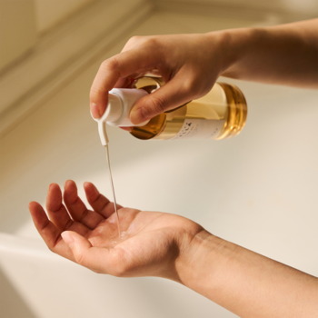 Skin1004 Madagascar Centella Light Cleansing Oil, złoty płyn wlewany z butelki z białą pompką do dłoni.