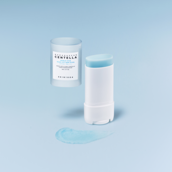 Otwarty biały sztyft przeciwsłoneczny SKIN1004 SPF 50+, błękitny produkt, osobna nakrętka i smużka na tle.