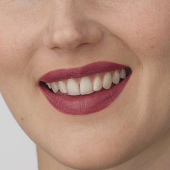 Uśmiechnięte usta z nawilżającą pomadką IsaDora Perfect Moisture Lipstick, kremowy odcień 15 Heather.