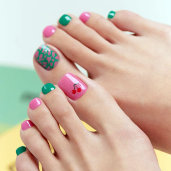Różowo-zielony pedicure Ohora Cherryz na stopach, z naklejkami w wisienki i nieregularne kropki.