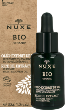 Nuxe Bio Organic Olejek Ryżowy na noc, ciemnozielona butelka z kroplomierzem, przed brązowym kartonowym pudełkiem.