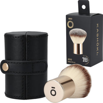 Kashōki Kabuki Brush, pędzel do pudru z puszystymi, brązowo-białymi włóknami, ze złotą skuwką, obok etui i pudełko.