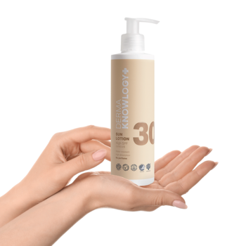 Hipoalergiczny balsam SPF 30 DermaKnowlogy w beżowo-białej butelce z pompką, trzymany w dłoniach.