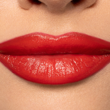 Usta z Pupa Milano Vamp! Creamy Duo Orange Red. Zbliżenie, intensywna, błyszcząca pomadka o kremowym wykończeniu.